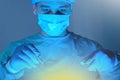 Close-up portrait of a caucasian doctor surgeon, in a sterile suit, mask, holding a scalpel and needle holder with a needle, Royalty Free Stock Photo