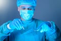 Close-up portrait of a caucasian doctor surgeon, in a sterile suit, mask, holding a scalpel and needle holder with a needle, Royalty Free Stock Photo