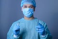 Close-up portrait of a caucasian doctor surgeon, in a sterile suit, mask, holding a scalpel and needle holder with a needle, Royalty Free Stock Photo