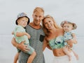 Close up portrait of Caucasian family spending time on the beach. Father and mother holding sons. Cute baby boys. Smiling parents Royalty Free Stock Photo