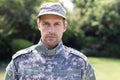 Close up portrait of caucasian male soldier wearing camo fatigues and cap standing in garden