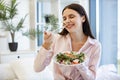 Portrait of relaxed woman sitting on comfy bed eating healthy salad. Royalty Free Stock Photo