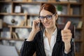 Close up portrait caucasian woman employee in glasses working in office talking on mobile phone