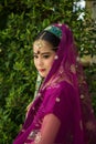 Close up portrait charming Asian woman wearing a purple Indian traditional saree with a green nature wall background