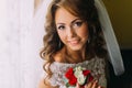 Close-up portrait of charming bride in wedding dress holding a cute bouquet with red and white roses Royalty Free Stock Photo