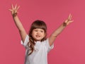 Close-up portrait of a little brunette girl dressed in a white t-shirt posing against a pink studio background. Sincere Royalty Free Stock Photo