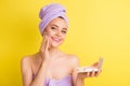 Close-up portrait of charming cheery girl wiping oily skin with napkin isolated over vibrant yellow color background Royalty Free Stock Photo