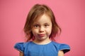 Close up portrait of charming little girl with serious look on pink isolated. Royalty Free Stock Photo