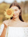 Close up portrait of charming woman holding sunflower. One eye is covered by sunflower. Beautiful face. Romantic mood Royalty Free Stock Photo