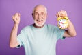 Close-up portrait of cheerful cheery glad pensioner holding in hand bell clock good time isolated over violate color