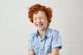 Close up portrait of cheerful little kid with curly ginger hair and freckles laughing with closed eyes after hearing Royalty Free Stock Photo