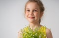 Close up portrait of a cheerful smiling little girl dressed in yellow holding bunch of field flowers in hands. Studio Royalty Free Stock Photo
