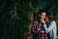 Close-up portrait of the cheerful smiling young couple near the wall overgrown with plants. The girl is stroking the Royalty Free Stock Photo