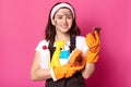 Close up portrait of cheerful sweet cleaning woman in white casual t shirt, brown apron and hair band, holds sponge, phone and