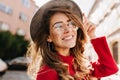 Close-up portrait of cheerful white woman in glasses touching her hat on blur background. Photo of fashionable girl with Royalty Free Stock Photo