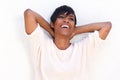 Close up cheerful young lady with hands behind head on white background