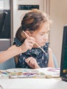 Close-up portrait of a child. Cute girl draws with paints. Ideas for activities with children at home. Vertical shot