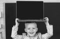 Close up portrait of child holding laptop on head, gadgets to study. Computer education for kids. Royalty Free Stock Photo