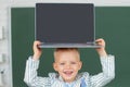 Close up portrait of child holding laptop on head, gadgets to study. Computer education for kids. Royalty Free Stock Photo