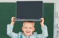 Close up portrait of child holding laptop on head, gadgets to study. Computer education for kids. Royalty Free Stock Photo