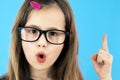 Close up portrait of a child school girl wearing looking glasses holding up point finger in I have an idea gesture isolated on