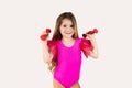 Close-up portrait, child, smiling, funny looking, happy little girl wearing pink gymnastics leotard, lifting dumbbells Royalty Free Stock Photo