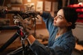 Close-up portrait of concentrated cycling mechanic woman checking and repairing bicycle handlebar with tools while Royalty Free Stock Photo