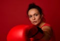 Close-up portrait of concentrated young sports woman boxer wearing red boxing gloves, making direct hit, punching towards camera, Royalty Free Stock Photo