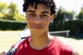 Close-up portrait of confident biracial young man with tennis racket smiling in tennis court Royalty Free Stock Photo