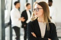 Close-up portrait of a confident business woman with her arms crossed and her colleagues behind her back. Royalty Free Stock Photo