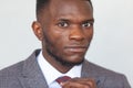 Close up portrait of confident handsome african business man in modern grey suit straightening his tie against a gray Royalty Free Stock Photo