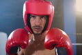 Close-up portrait of confident male boxer wearing red headgear and gloves