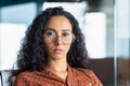 Close-up portrait of confident serious business woman, hispanic woman wearing glasses inside office looking at camera