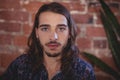 Close up portrait of confident young male photographer against brick wall Royalty Free Stock Photo