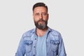 Close up portrait of confident young man with beard looking at camera with serious facial expression, wearing gray casual shirt Royalty Free Stock Photo