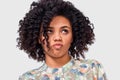 Close-up portrait of confused African American young woman student has dilemma expression, frowns her face and looking up.