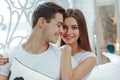 Close-up portrait couple in love is hugging. Beautiful young couple is sitting on bed in bedroom. Enjoying spending time together Royalty Free Stock Photo