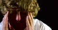 Close-up portrait of a curly-haired man on a black background. Headache from the problems of life depression.