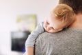 Close-up portrait of cute adorable blond caucasian toddler boy sleeping on fathers shoulder indoors. Sweet little child feeling Royalty Free Stock Photo