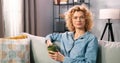 Close up portrait of the cute attractive blonde lady sitting at the sofa and enjoying calm holidays. Lovely pretty curly Royalty Free Stock Photo