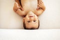 Close-up of the portrait of a cute baby boy. The little sweet toddler is lying on the bed. The smiling child is being held by his Royalty Free Stock Photo