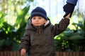 Baby Boy Wearing A Blue Knit Winter Hat And Green Winter Parka Royalty Free Stock Photo