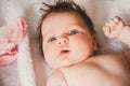 Close-up portrait of cute baby girl lying down on a white bed. Looking at camera. Big open eyes. Healthy little kid Royalty Free Stock Photo