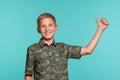 Close-up portrait of a blonde teenage boy in a green shirt with palm print posing against a blue studio background Royalty Free Stock Photo