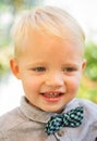 Close up portrait of cute boy with bowtie smiling outdoors. Closeup headshot portrait of smiling little boy on nature Royalty Free Stock Photo