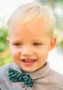 Close up portrait of cute boy with bowtie smiling outdoors. Closeup headshot portrait of smiling little boy on nature Royalty Free Stock Photo