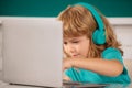 Close up portrait of cute boy wearing headphones, study with laptop in classroom, listening audio lesson course. Royalty Free Stock Photo