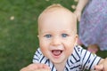 Close-up portrait of cute caucasian baby boy smiling and having fun with parents outdoors. Happy infant face with big