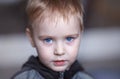 Close up portrait of cute caucasian baby boy with very serious face expression. Bright blue eyes, fair hair. Strong emotions. Royalty Free Stock Photo