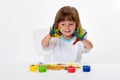 Close-up portrait of a cute cheerful happy smiling little girl draws her own hands with gouache or finger paints isolated on white Royalty Free Stock Photo